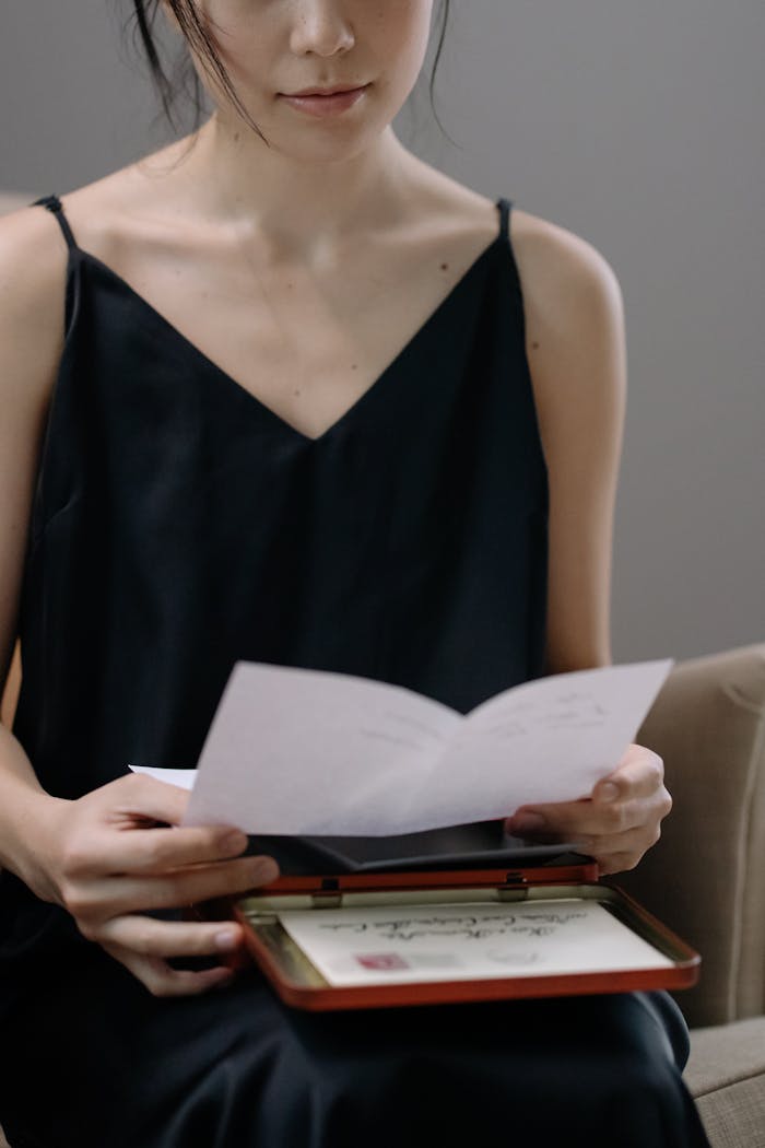 A woman sits in a cozy armchair, reading letters for a moment of tranquility.